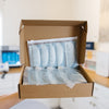 Open cardboard box containing  AO2 clear plastic bags with text, in an esthetician's office.