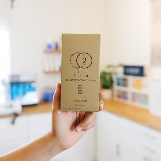 Hand holding a beige box labeled CO2 'Lift Pro' in an esthetician's office.