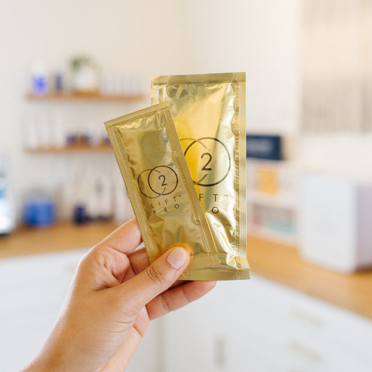 Hand holding a beige box labeled CO2 'Lift Pro' in an esthetician's office.