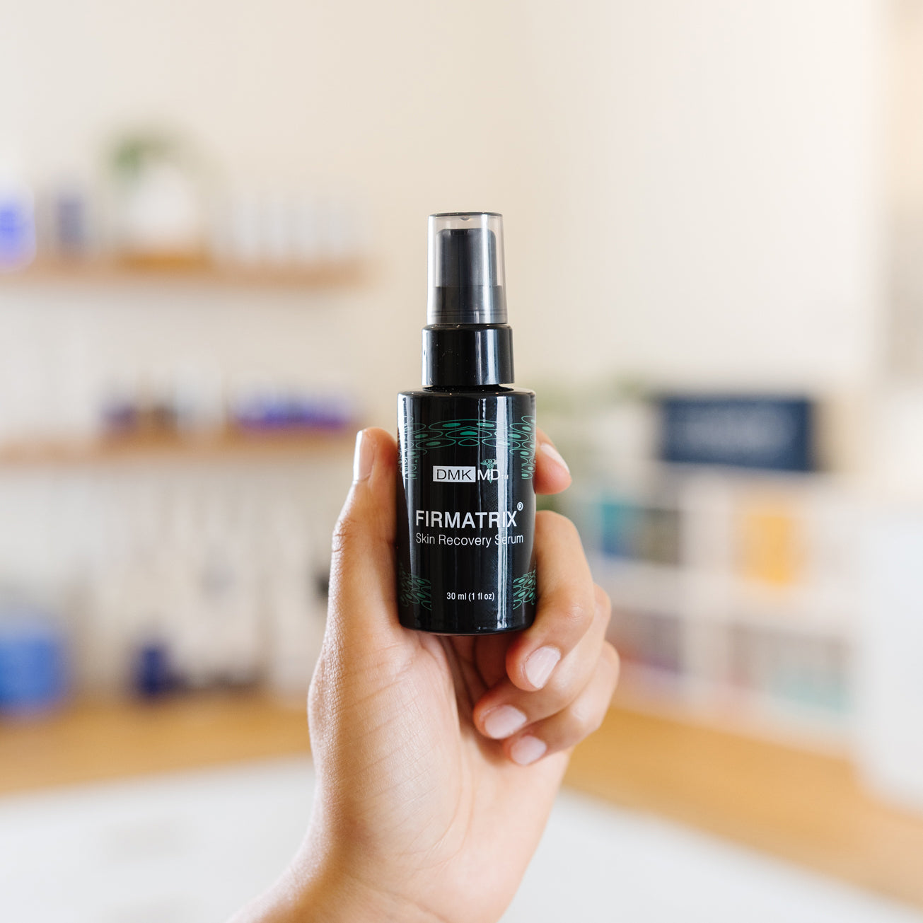 Holding a bottle of DMK Firmatrix Skin Recovery Serum in an esthetician's office.