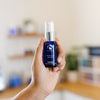 Hand holding a skincare iS Clinical Hydra Cool Serum bottle in an esthetician's office.