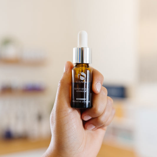 Hand holding a iS Clinical Super Serum Advance+ bottle in an esthetician's office.