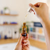 Hand holding a dropper of iS Clinical Super Serum Advance+ bottle in an esthetician's office.