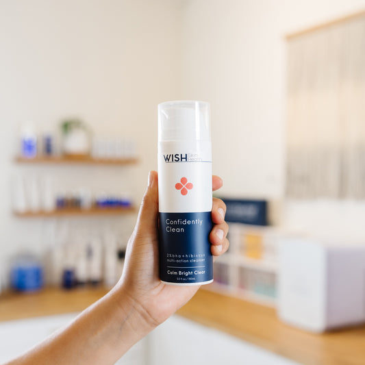 Hand holding a 'Wish' Confidently clean product in an esthetician's office.