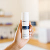 Hand holding a skincare product labeled 'Wish Azelify' in an esthetician's office.