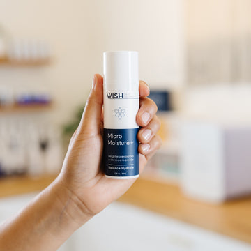 Hand holding a Wish Micro Moisture+ bottle in an esthetician's office.