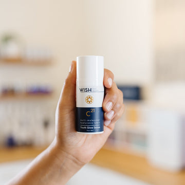 Hand holding a bottle of Wish C21 Youth Glow Serum