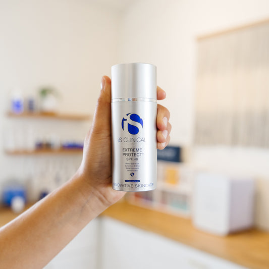 Hand holding a bottle of IS Clinical Extreme Protect SPF 40 sunscreen in an estheticians office