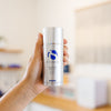 Hand holding a bottle of IS Clinical Eclipse SPF 50 sunscreen in an estheticians office