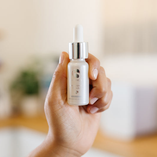 Person holding a bottle of iS Clinical Brightening Serum in an estheticians office