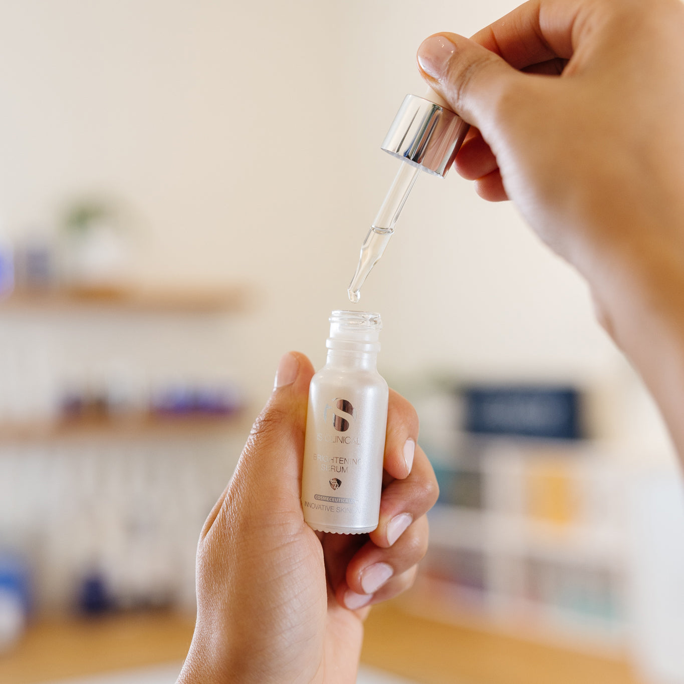 Person holding a bottle of iS Clinical Brightening Serum in an estheticians office