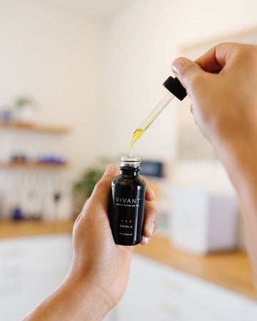 Person using a dropper to extract liquid from a Vivant skincare bottle.