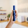 Hand holding a blue iS Clinical Genexc Firming Eye Gel bottle in an estheticians office