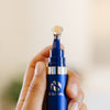Hand holding a blue iS Clinical Genexc Firming Eye Gel bottle in an estheticians office