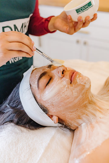 Person receiving a facial treatment with DMK branding.