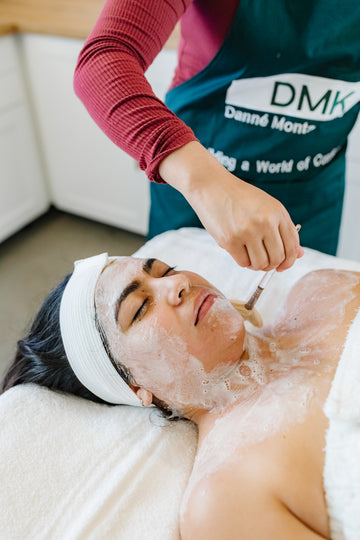 Person receiving a DMK facial treatment with DMK branding visible