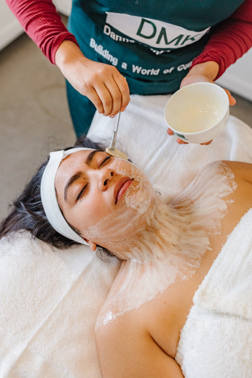 Person receiving a DMK facial treatment with a professional in a spa setting.